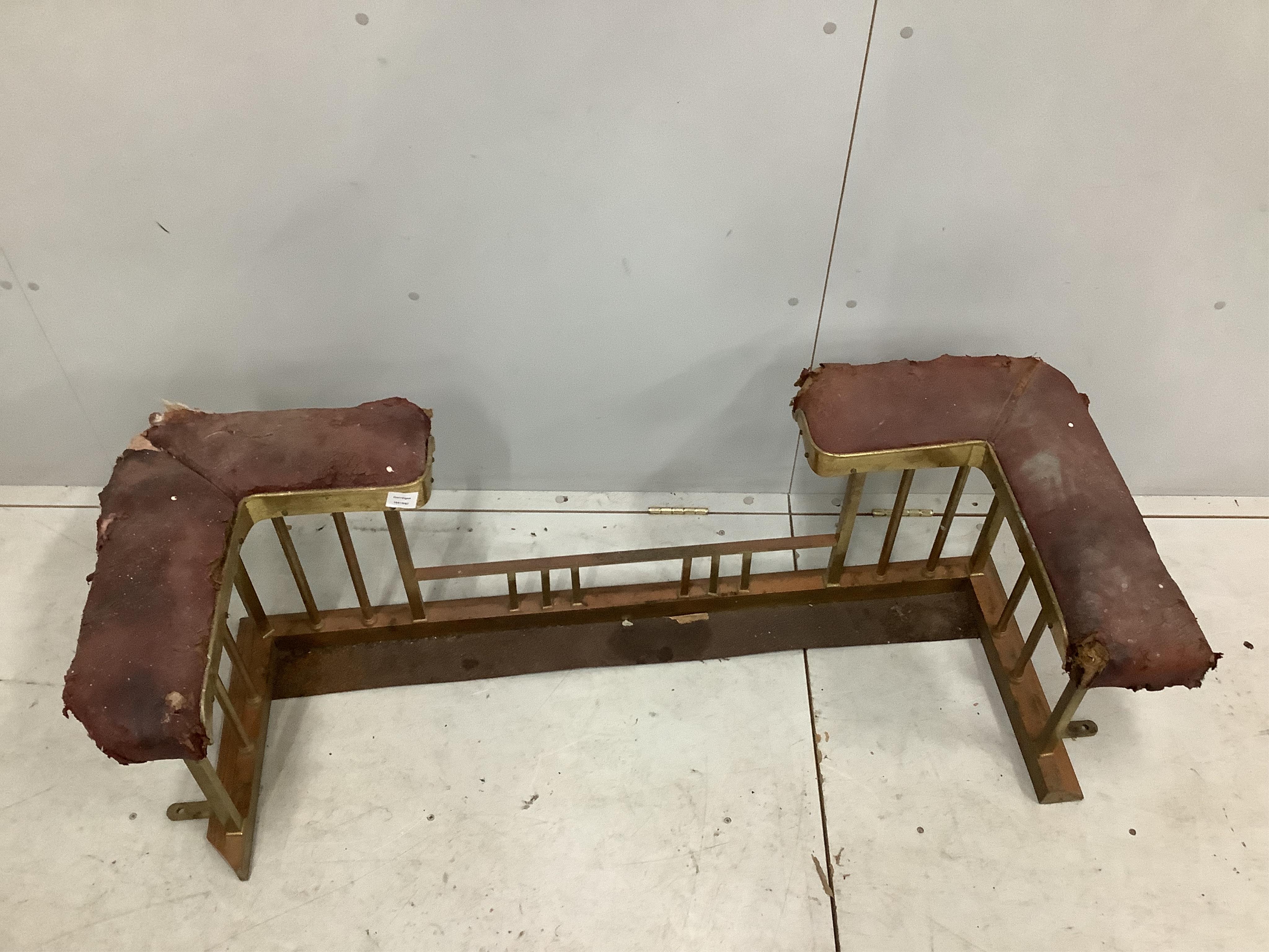 An Edwardian iron and brass club fender, width 128cm, depth 50cm, height 44cm. Condition - poor and in need of restoration, red leather seats will need replacing, metalwork tarnished, rear right side cut to accommodate a